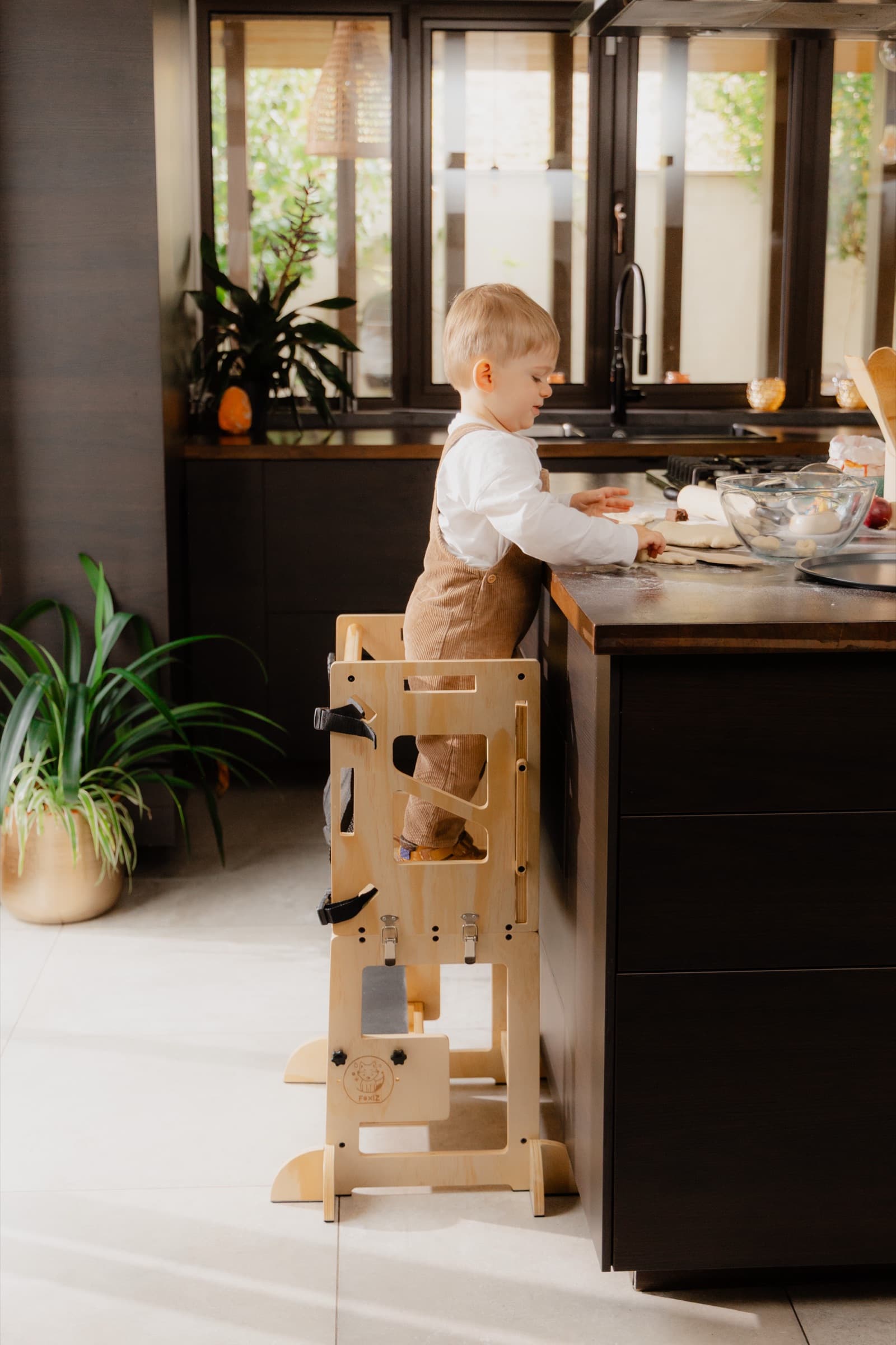 Enfant debout dans la tour d'apprentissage Montessori VersaTower, à hauteur du plan de travail