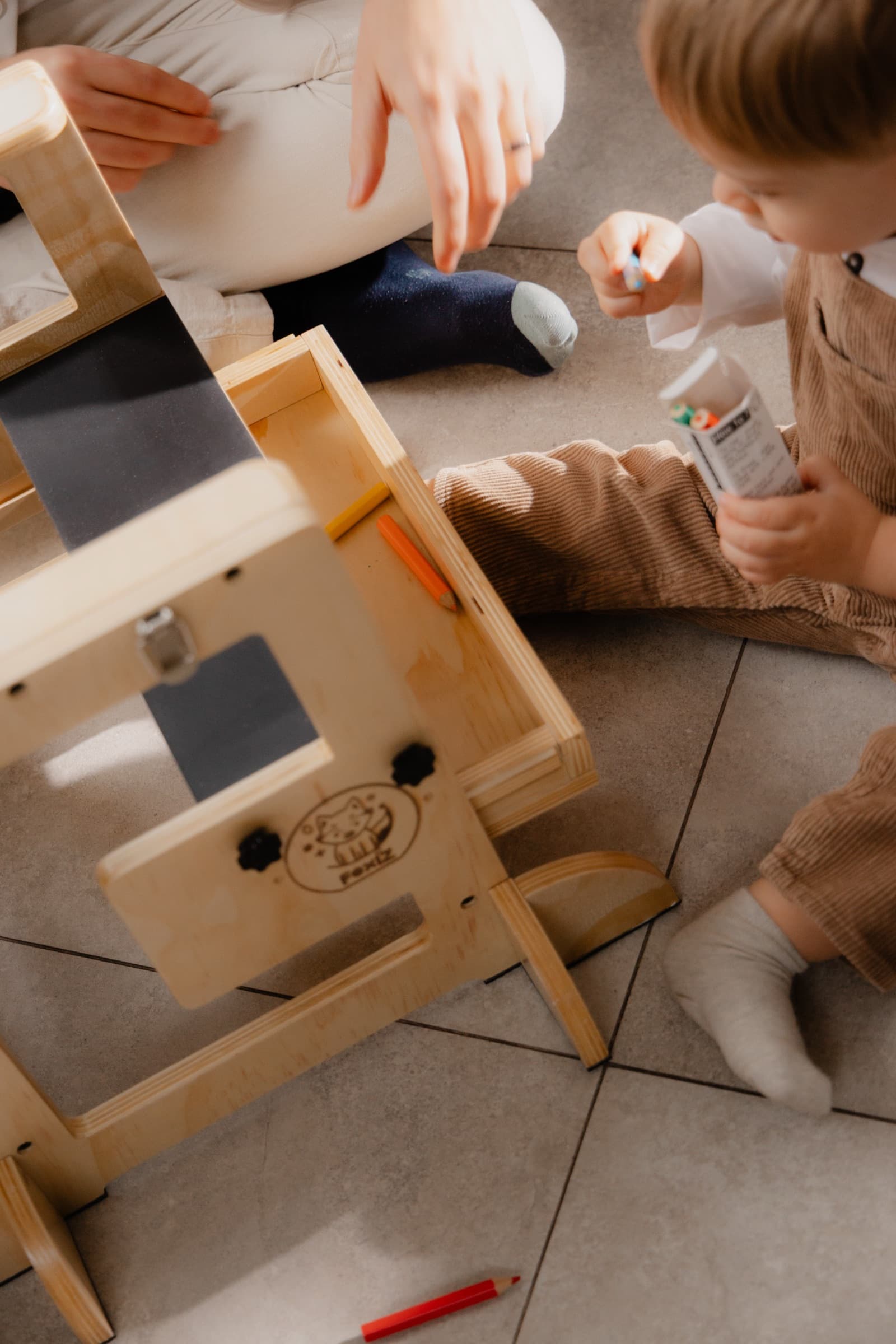 Parent et enfant assemblant ensemble la VersaTower, tour d'apprentissage Montessori