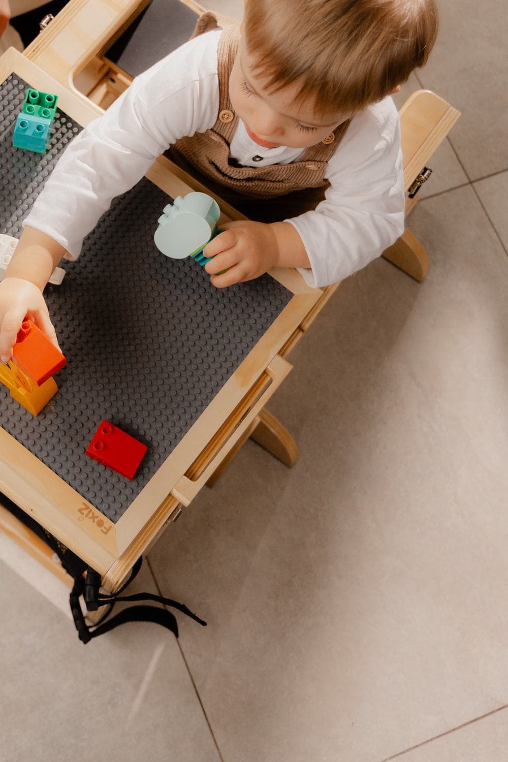 Enfant jouant avec des briques de construction sur le plateau réversible de la VersaTower